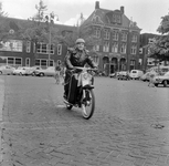 125569 Afbeelding van een bromfietser op het Domplein te Utrecht, met op de achtergrond het Dienstgebouw van de ...
